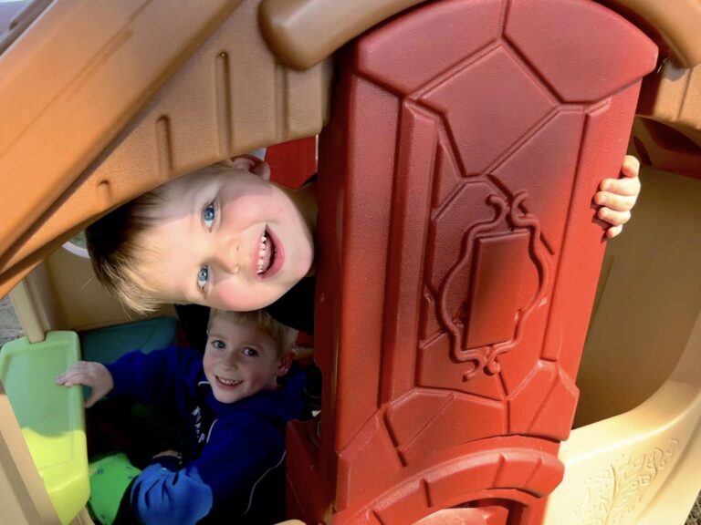 Photo of two preschool kids smiling in playhouse