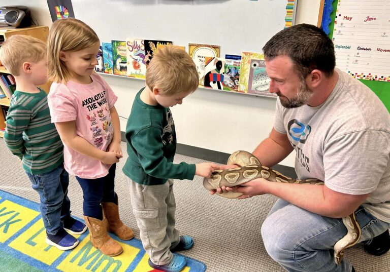 Photo of preschool kids lined up to pet a snake.